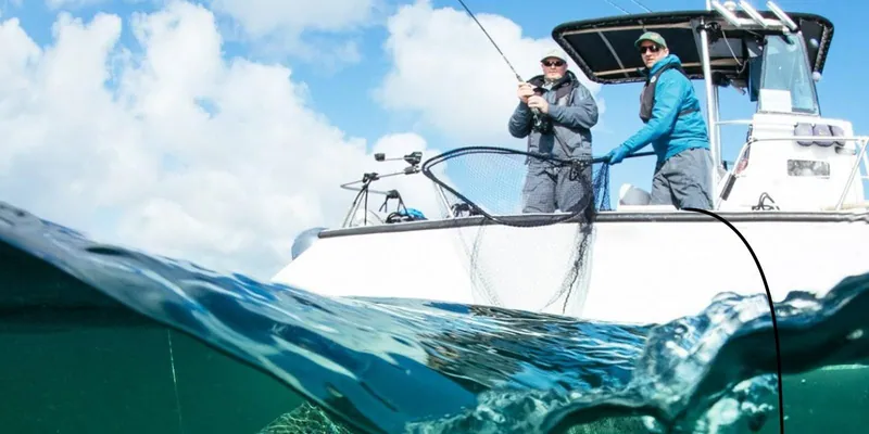 Two anglers fishing from a boat, seen at the waterline