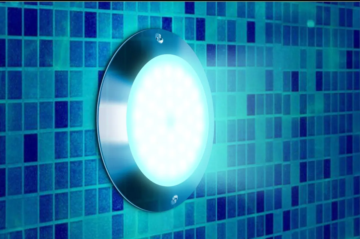 The Goldlife P9-2 pool light glowing on a blue mosaic pool wall